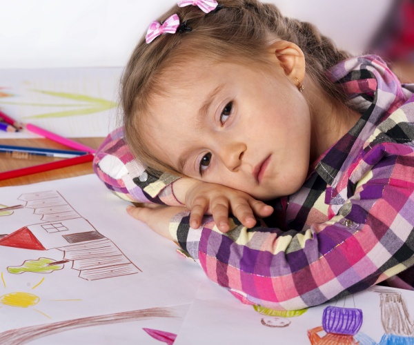 young girl with head on table feeling tired