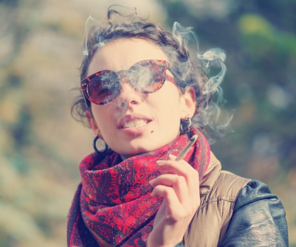 young woman smoking a cigarette outside