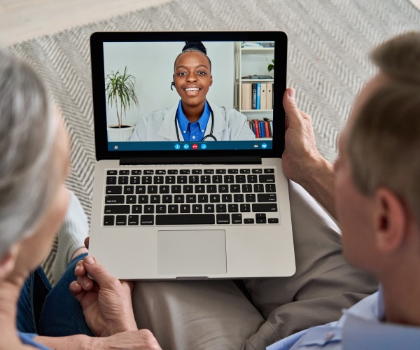 an older couple talking to their doctor on a laptop screen for a telehealth appointment