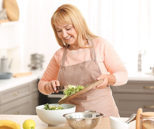 woman in kitchen making a salad