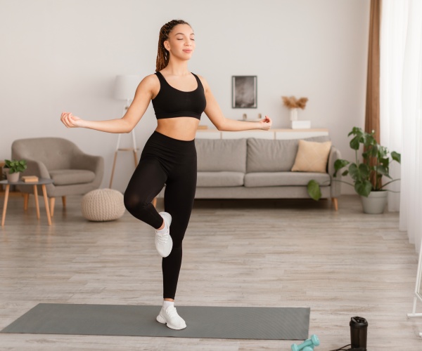 woman standing in a yoga pose with one leg up, eyes closed