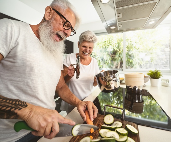 older couple working together in kitchen, smiling