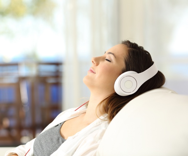 woman relaxing on couch listening to music with headphones