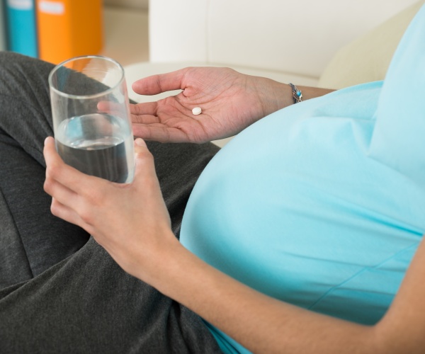 pregnant woman taking medication with glass of water