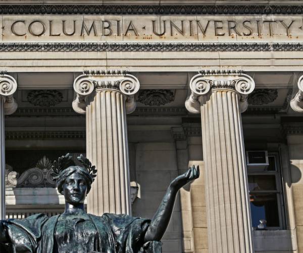 a statue and columbia university sign on a building 