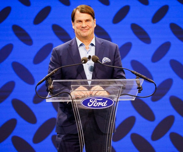 jim farley smiles from a podium