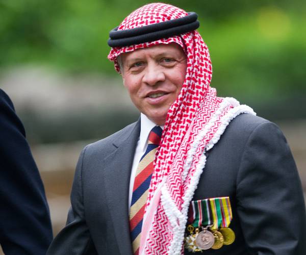 a man wearing a keffiyeh or head scarf and a business suit