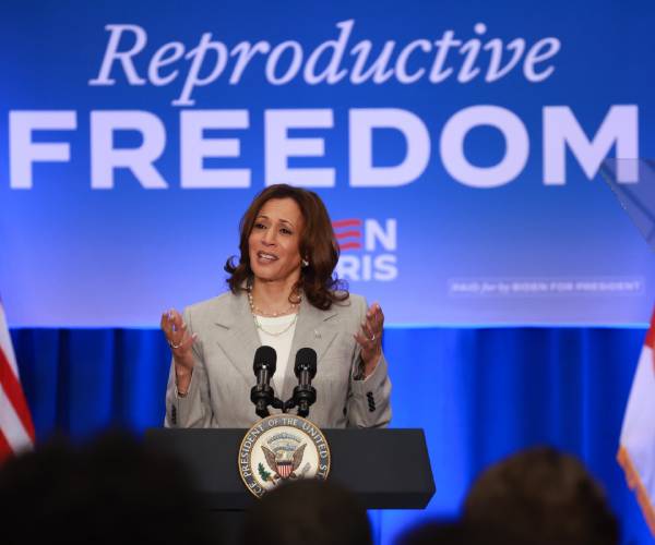 kamala harris speaking in front of a sign reading reproductive freedom