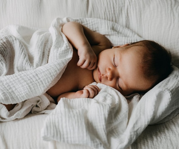 baby sleeping under white blanket