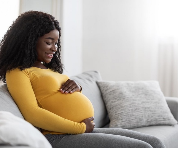 young pregnant woman sitting on couch