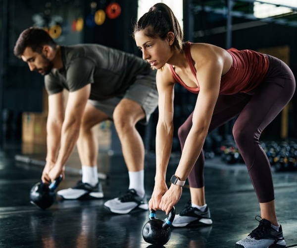 man and woman lifting weights at gym