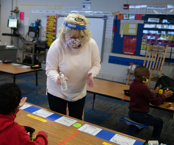 a teacher offers hand sanitizer to students