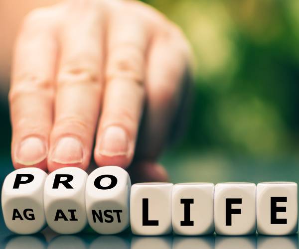 a hand rolling over dice that said against life to now read pro life