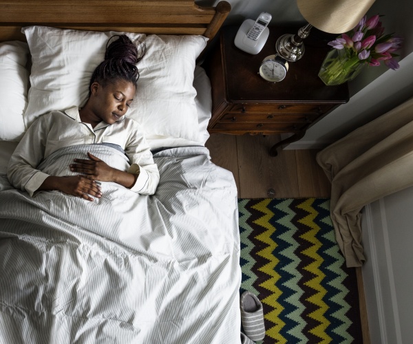 woman sleeping soundly in bed with hands on stomach 