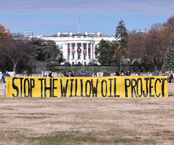 a large banner reading stop the willow oil project with the white house in the background