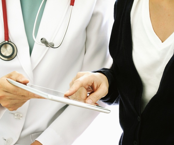 patient pointing to a tablet screen, asking doctor questions