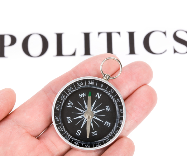 a hand holding a compass under the word politics