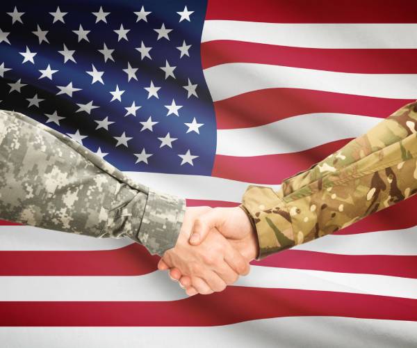 an american flag with two soldiers shaking hands in front of it