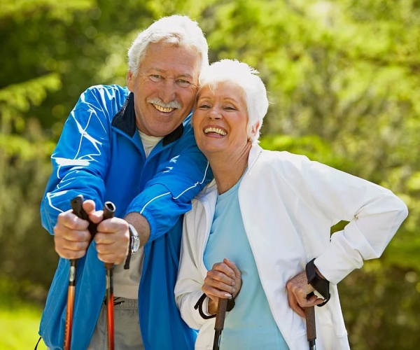 an older woman and man walking with walking sticks