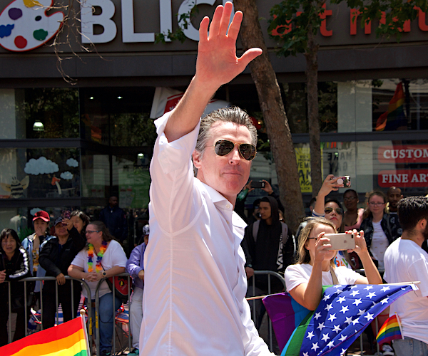 gavin newsom smiles and waves at a california pride parade