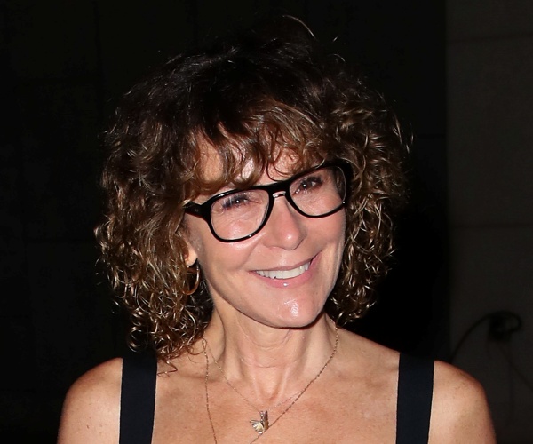 livingston in a black sleeveless dress wearing black rimmed glasses