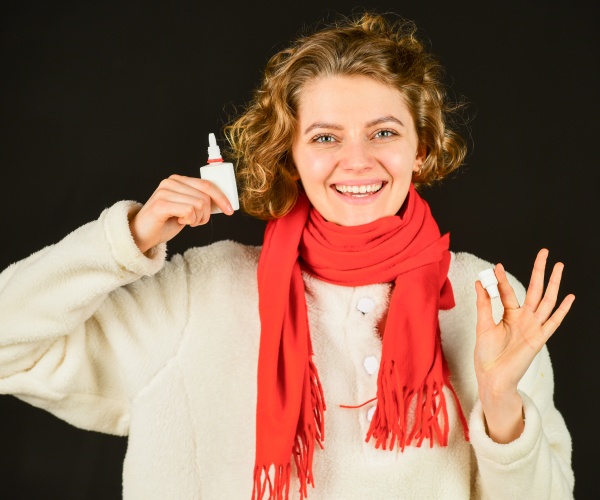 woman smiling and holding a nasal spray