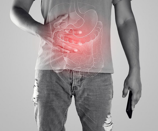 young man holding stomach with illustration of colon in red 