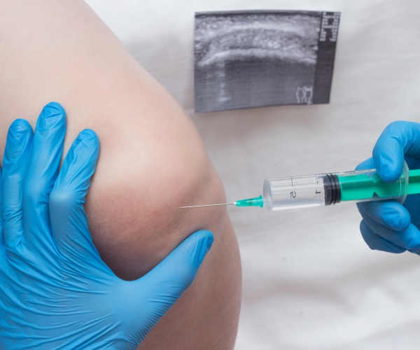 doctor injecting a patient's knee with steroid for pain