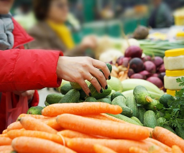 woman in produce section of market choosing vegetables