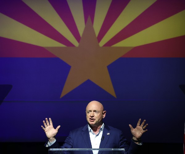 kelly standing before a crowd with a giant arizona state flag behind him