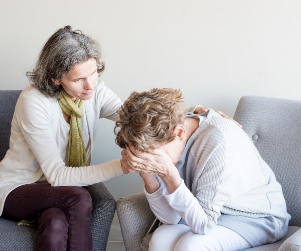 woman on couch crying, talking to therapist