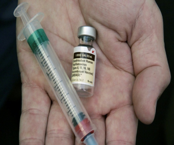 Hand holding vial of HPV vaccine and a syringe