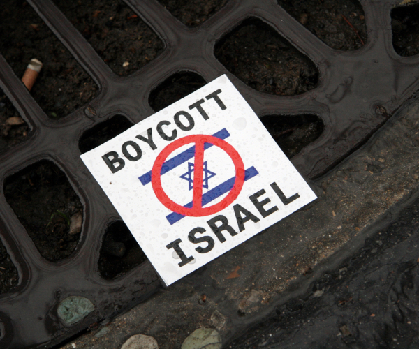 a flyer on the ground reading boycott israel with an israel flag and a red circle and line through it