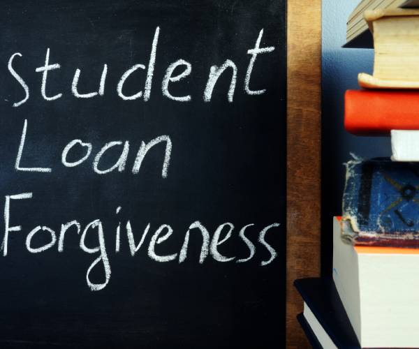 student loan forgiveness written on a chalkboard beside a stack of books