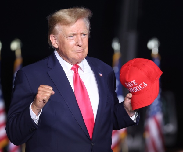 donald trump holds a cap in his hand