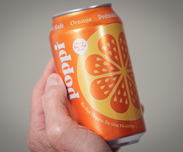 man's hand holding a can of Poppi orange soda