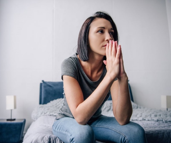 woman sitting on bed looking anxious, depressed