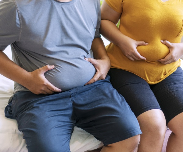 man and woman sitting and holding their bellies