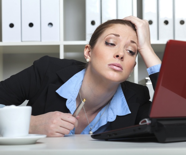 woman looking tired, unmotivated at work in front of computer