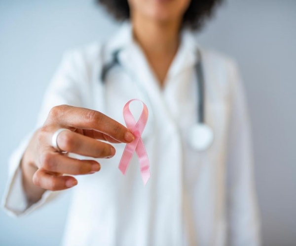 woman holding up a pink ribbon for breast cancer awareness