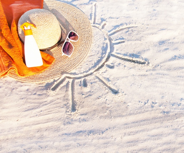 sunscreen, hat, sunglasses on the sand at beach