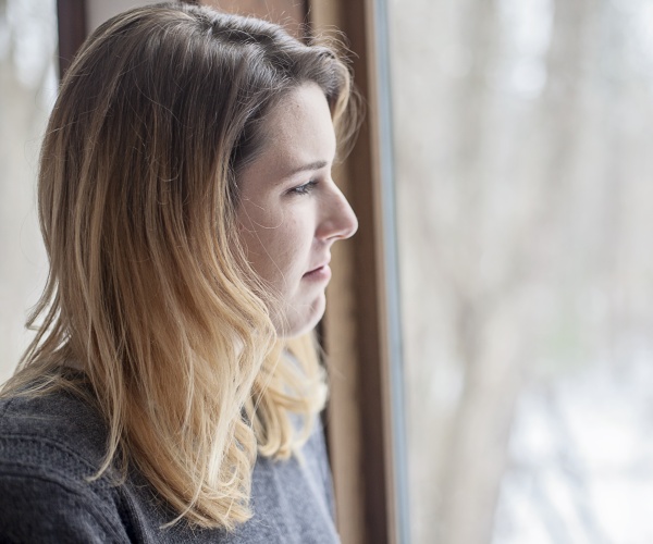 woman looking sad looking out window at snow