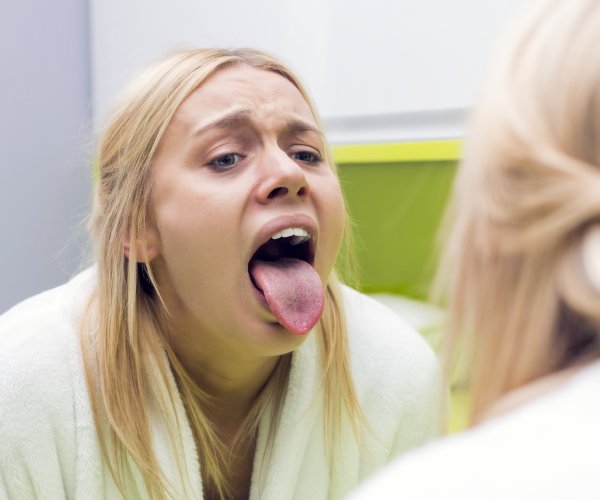 woman examining tongue in mirror