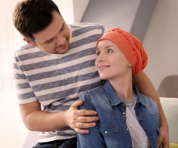 man hugging woman with cancer, scarf on her head