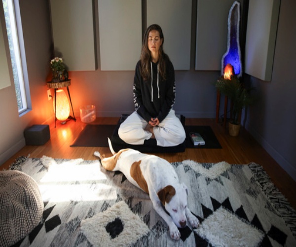 woman in room with dog practicing meditation