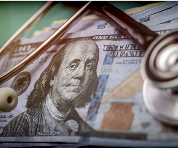 a stethoscope sitting on top of hundred dollar bills