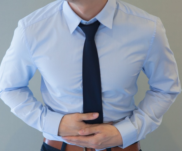 man in business clothes holding stomach 