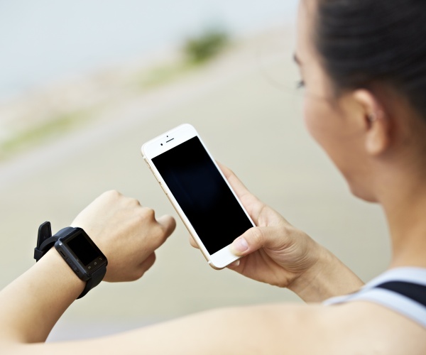 woman looking at fitness watch, cell phone