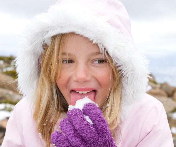 young girl outside eating snow