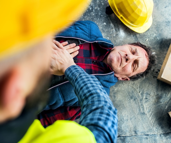 man getting cpr on ground at construction site